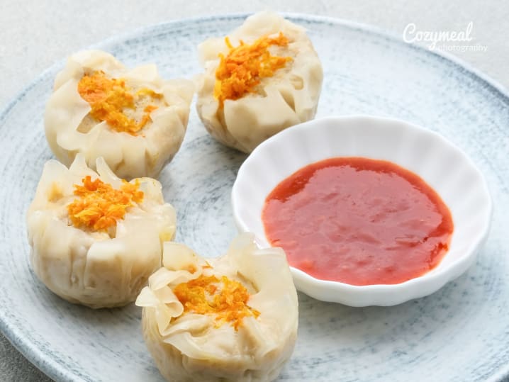 shumai dumplings on a pastel plate with a dipping sauce on the side