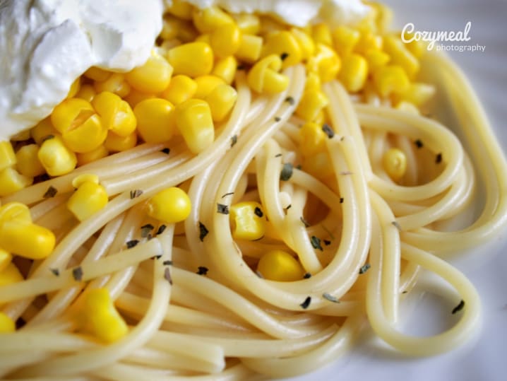 Spaghetti with corn and whipped ricotta â€“ A plate of spaghetti topped with sweet corn kernels, cracked pepper, and a dollop of whipped ricotta.