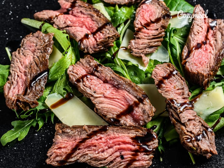 sliced steak tagliata served with fresh arugula and shaved parmesan