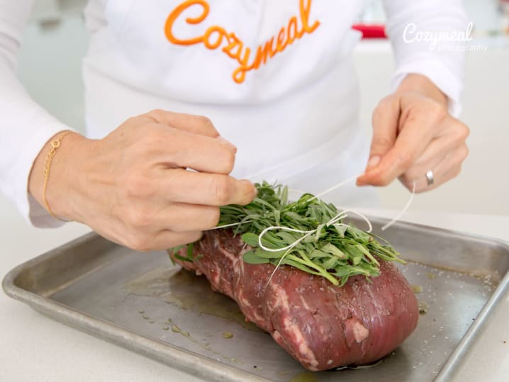 tying beef tenderloin with herbs