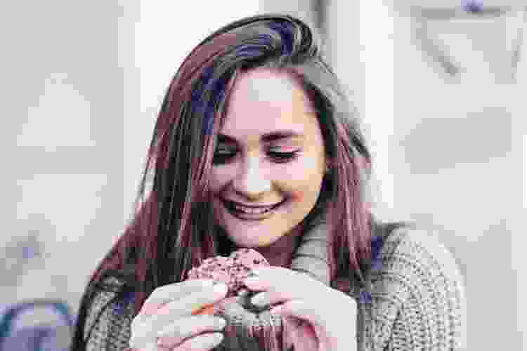 a smiling young woman holding a cookie