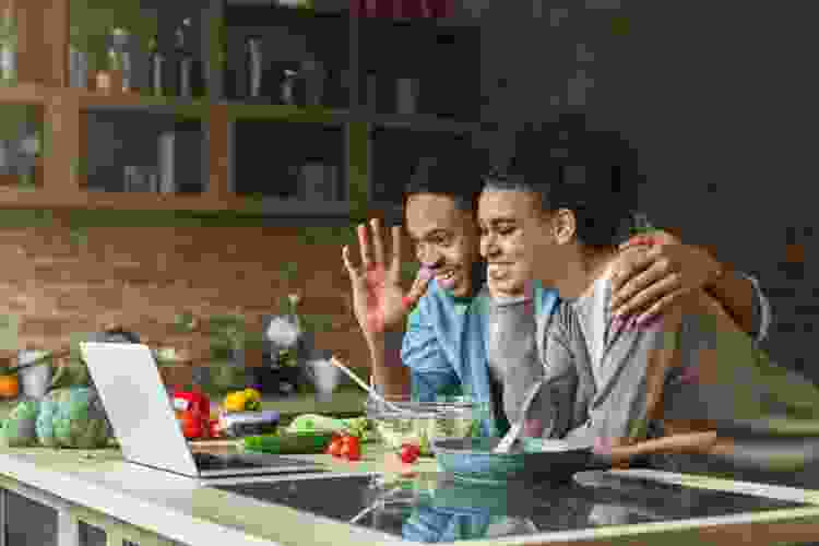 couple taking an online cooking class in their kitchen