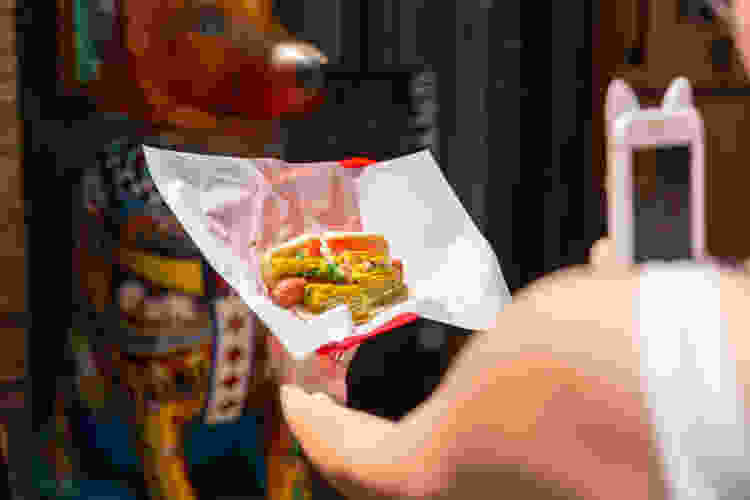 woman holding a chicago style hot dog on a food tour