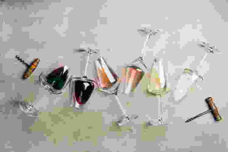 glasses filled with different wines with a corckscrew