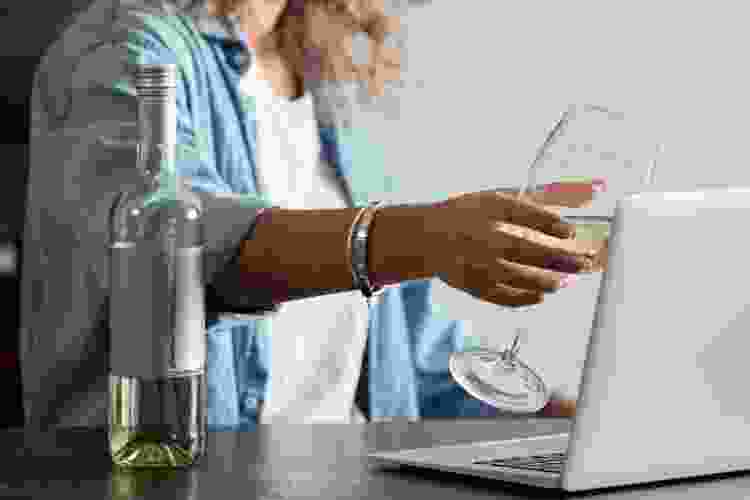 woman raising a glass of wine during virtual wine tasting