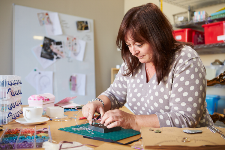 woman adding beads to string to make jewelry