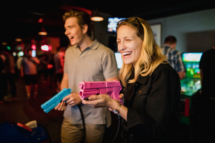couple playing shooting games at adult arcade