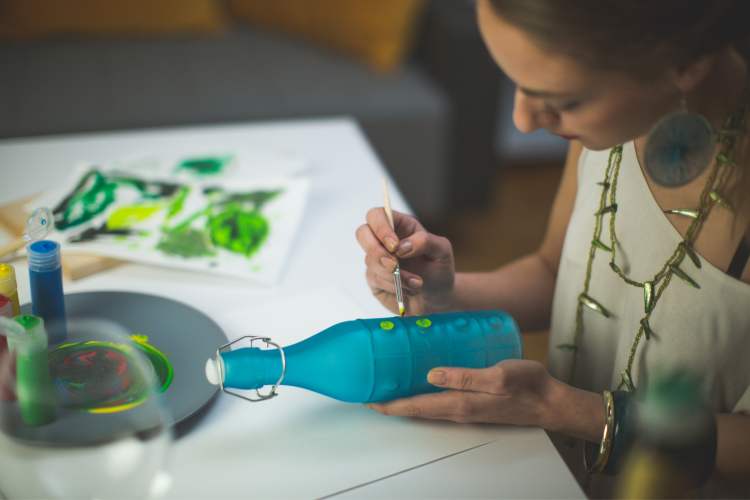 woman painting blue glass jar