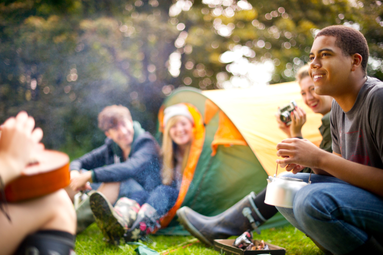 teens camping out with tents and bonfire in backyard