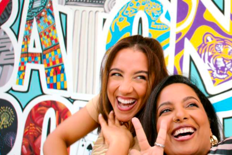 two young women posing in front of Baton Rouge mural