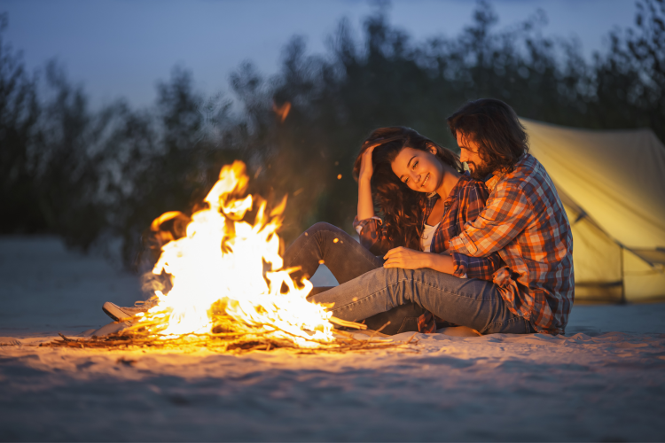 couple snuggled by bonfire on the beach