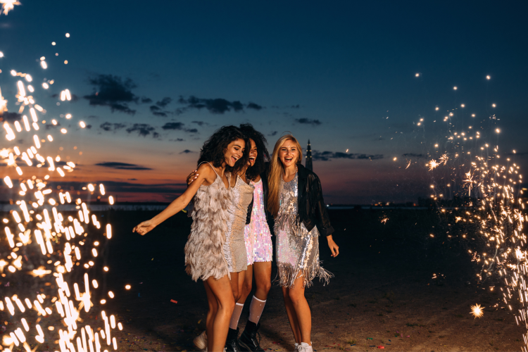women dancing on the beach with sparklers