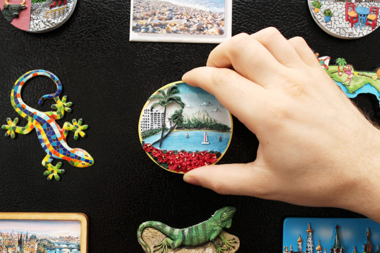 hand placing ceramic beach magnet on the fridge