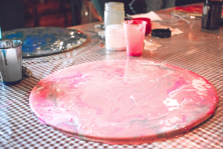 pour painting pink and white paint onto round tray