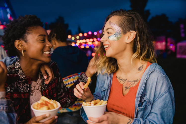 two young women eating food at festival