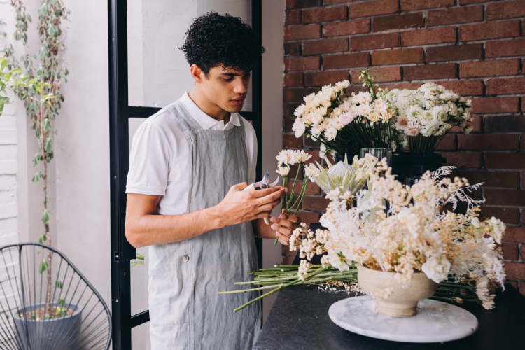 man arranging white flowers into a vase