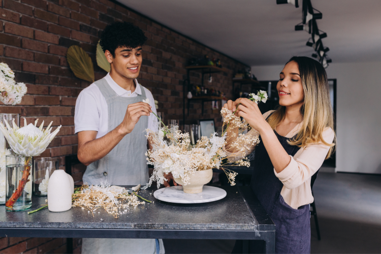 couple arranging white flowers into vases