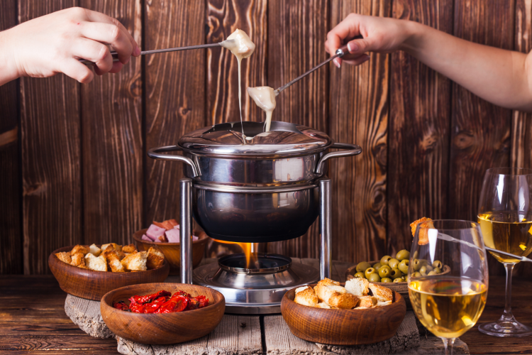 hands dipping food in fondue