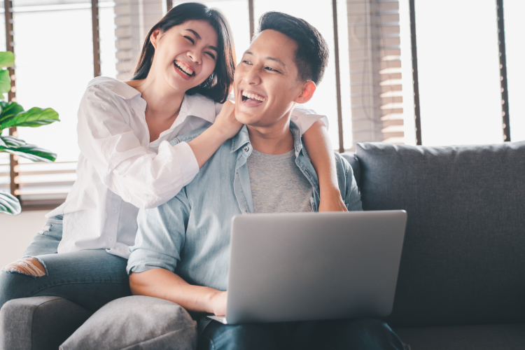 couple laughing while playing games on laptop