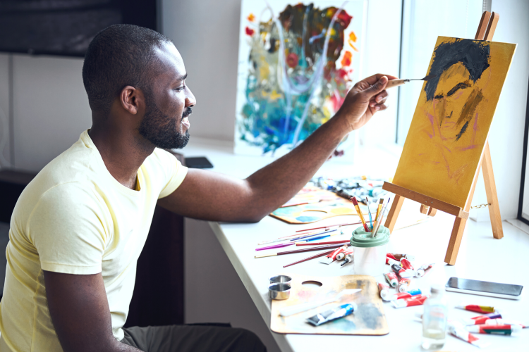 man painting on canvas with palette knife