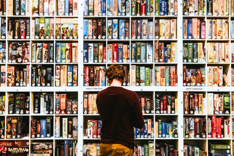 Man looking at boardgames displayed on a wall