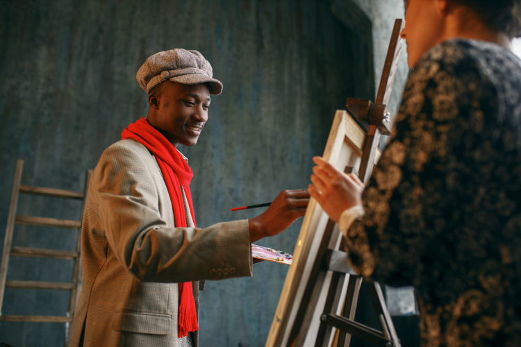 young man painting art on canvas and easel