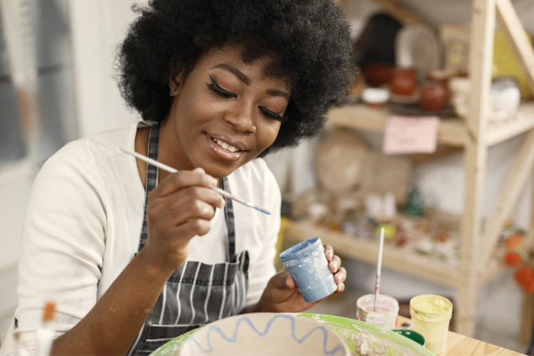 woman painting pottery in pottery studio