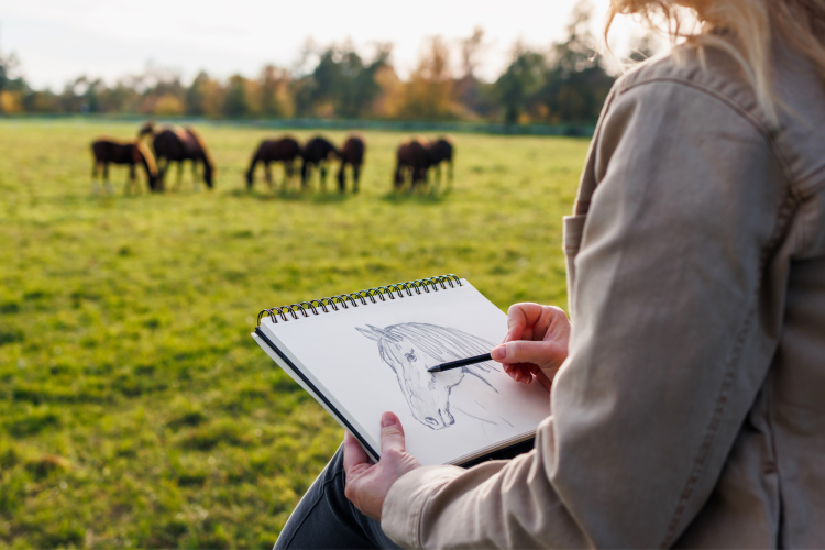 woman finding art inspiration in nature by drawing in plein air