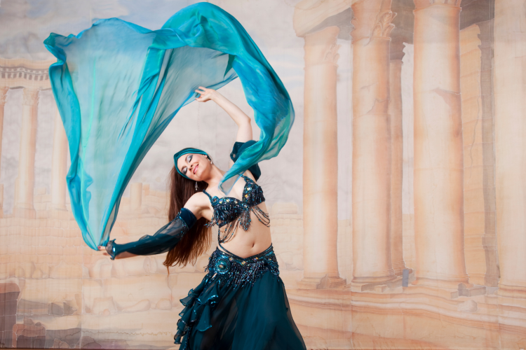 woman in blue dress belly dancing with scarf