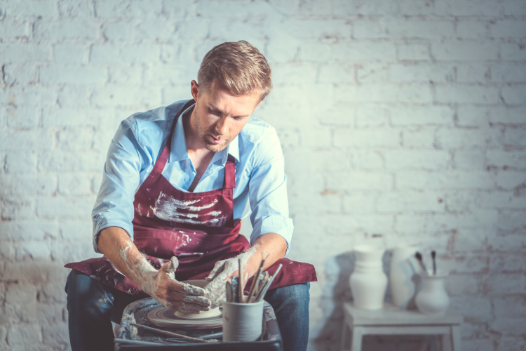 man molding clay on pottery wheel
