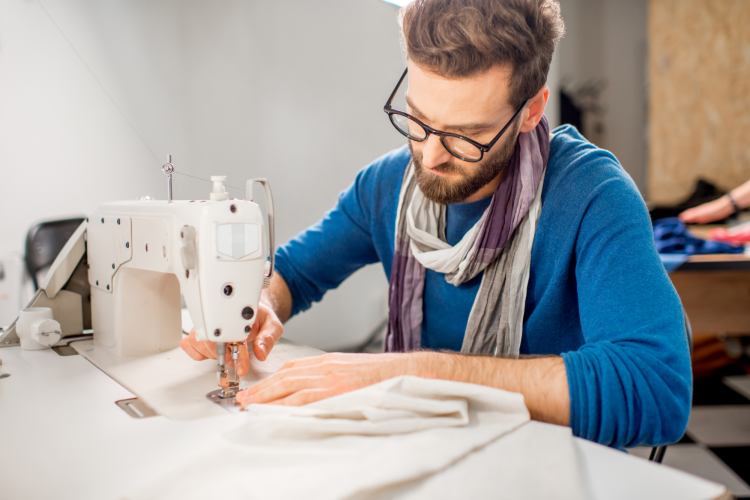 man sewing fabric with sewing machine