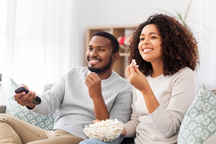 couple watching movie with popcorn at home