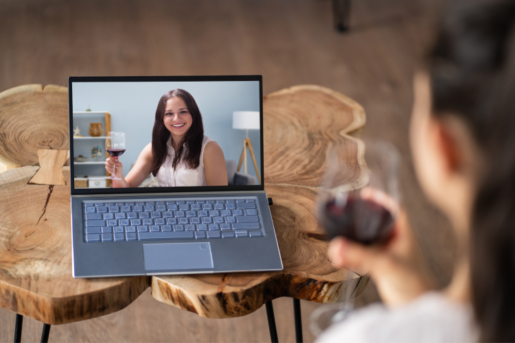 two women drinking wine over online video call
