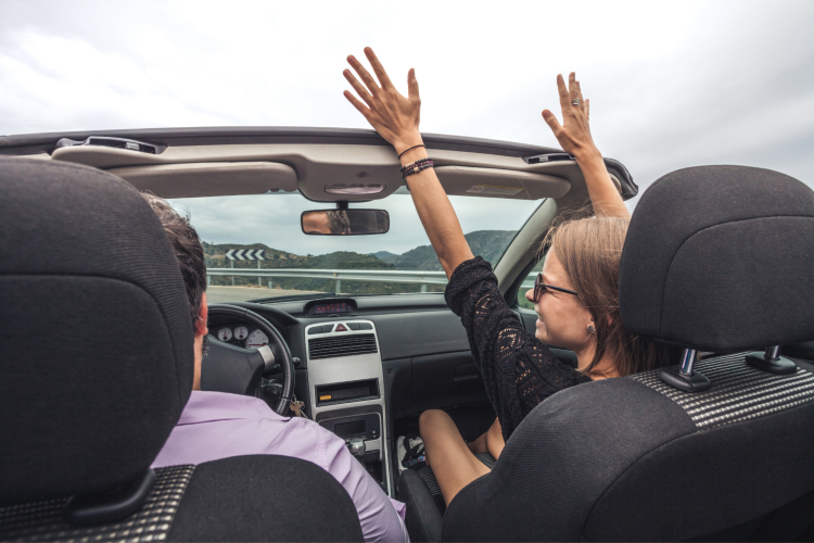 friends in convertible with hands in the air
