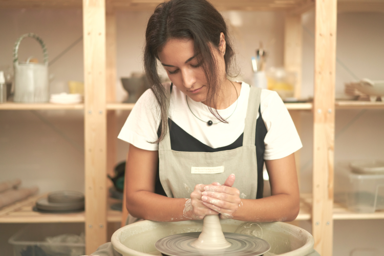 woman molding clay using a potters wheel