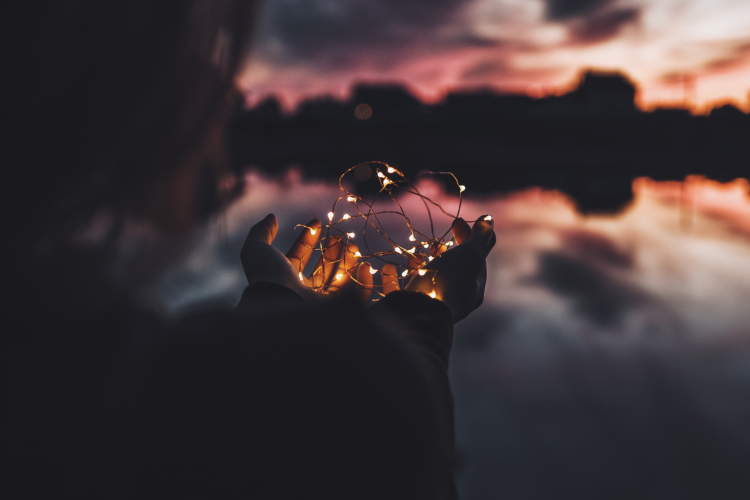 Woman holding fairy lights at sunset