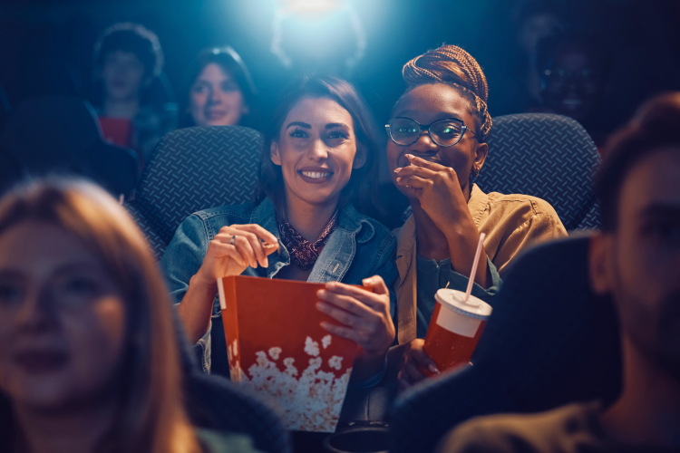 happy female friends watching movie cinema