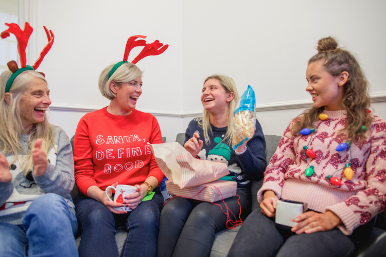 friends asking secret santa questions while wearing ugly sweaters