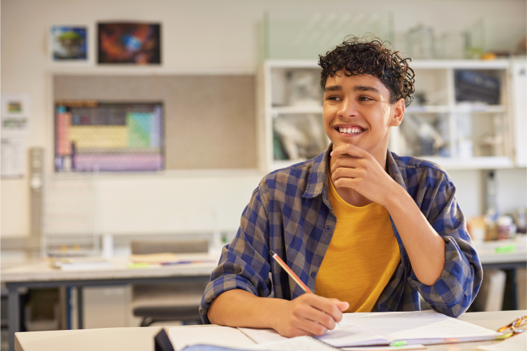 teen boy thinking and smiling while writing