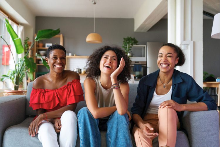 three woman sitting on a sofa and laughing
