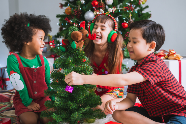 diverse kids laughing by a Christmas tree