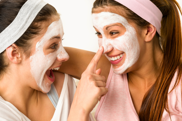 two ladies smiling and putting on a face mask