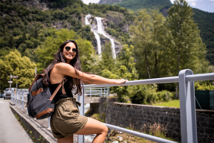 woman traveling alone and standing in front of a waterfall