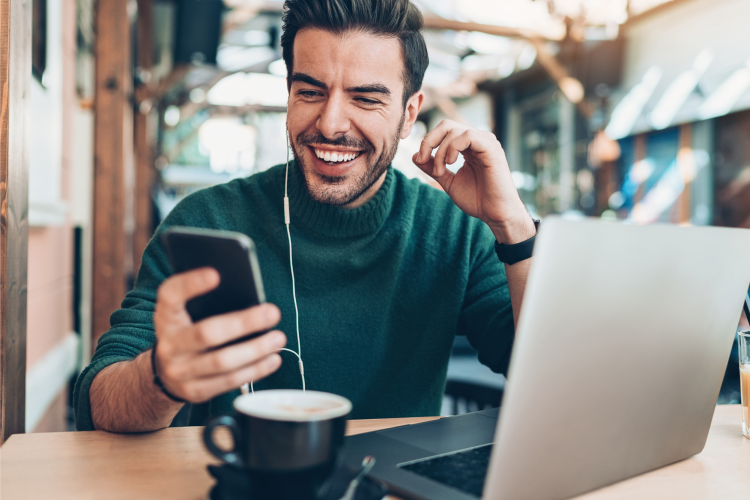 man looking at his phone while drinking coffee at a cafe