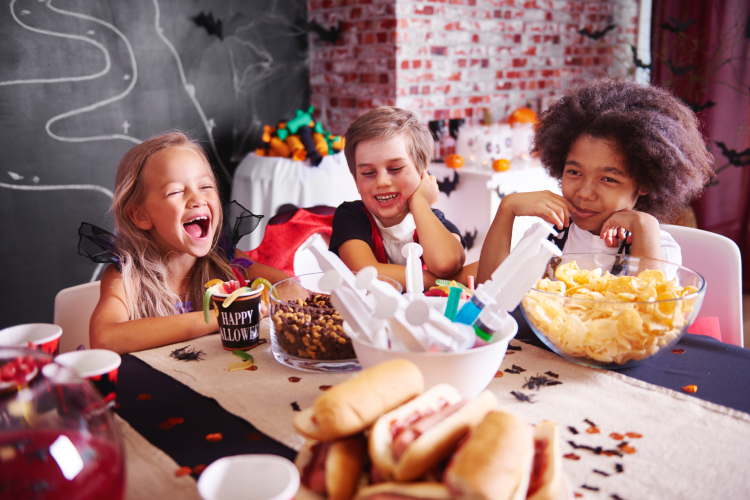 group of diverse kids eating candy and laughing during halloween