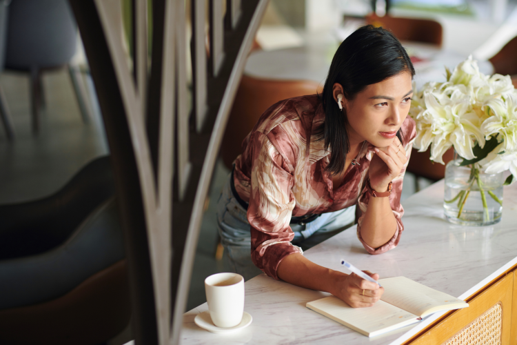 woman listening to music and writing in her gratitude journal