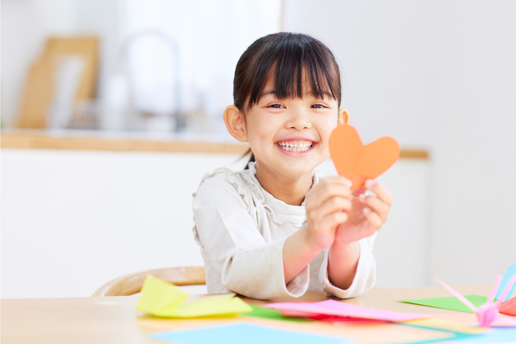 little girl smiling and holding a heart