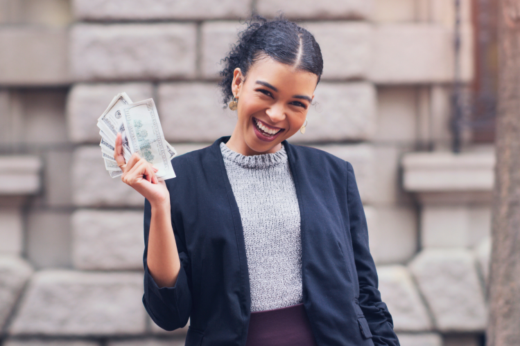 young businesswoman smiling while holding stack money