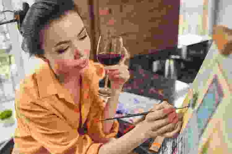 woman sipping wine and painting art on canvas