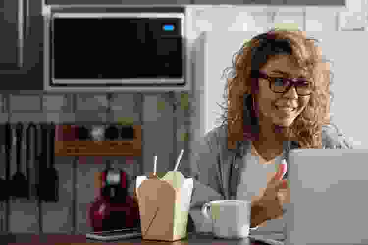 woman eating takeout and playing games over video chat